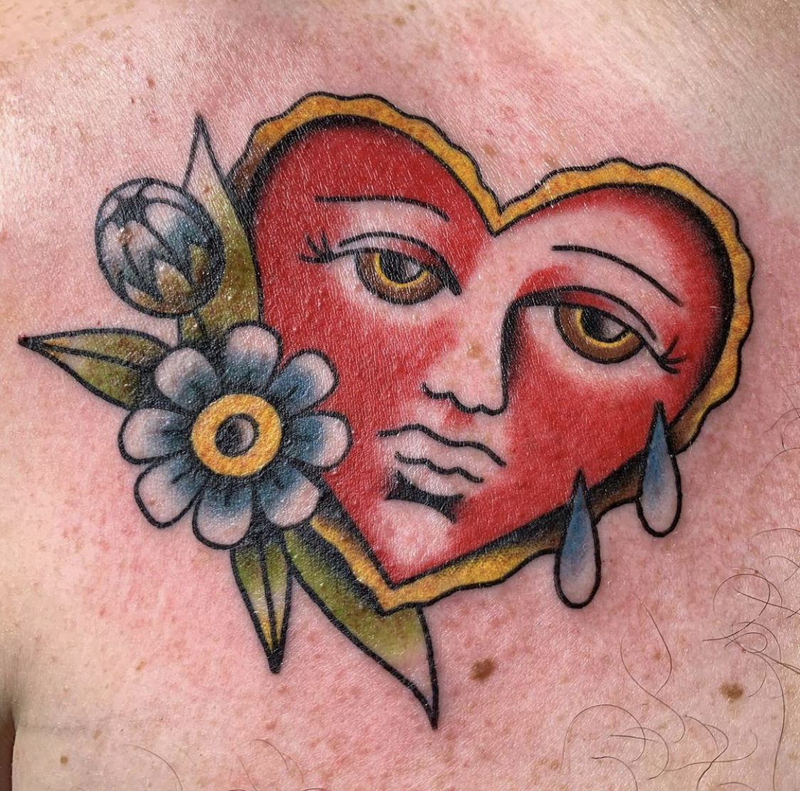 A crying heart with flowers beside it.