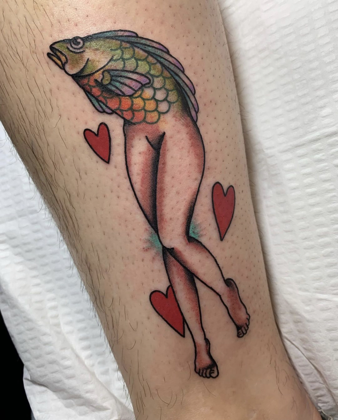 Hearts surround a mermaid with the top half of a fish and the bottom half of a human.