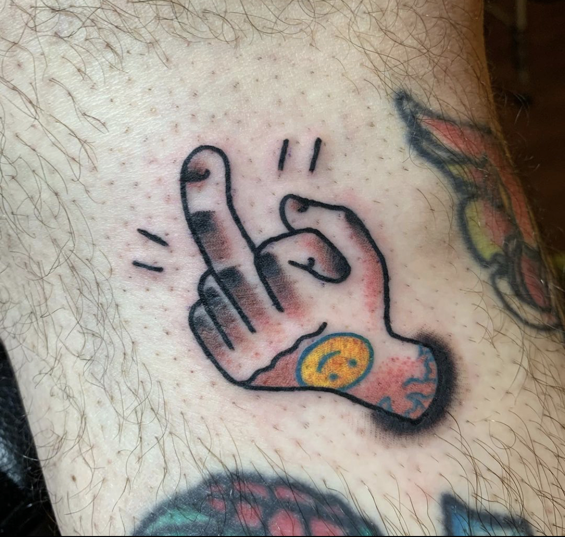 A middle finger with a smiley face tattooed on the back of the hand.